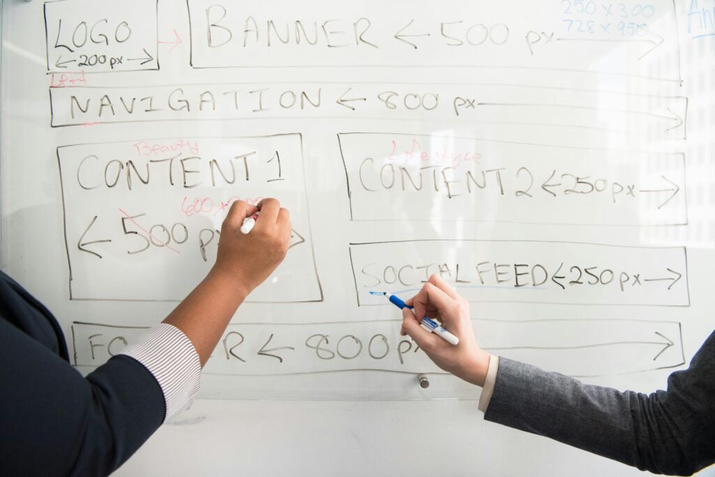 Two people collaboratively planning on a whiteboard with creative strategy.